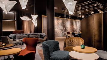 A modern interior with a dark color scheme, featuring a sofa, armchairs, and a round table with a green vase.