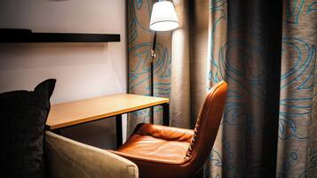 A corner of a room with a wooden table, a brown leather chair, and a lamp.
