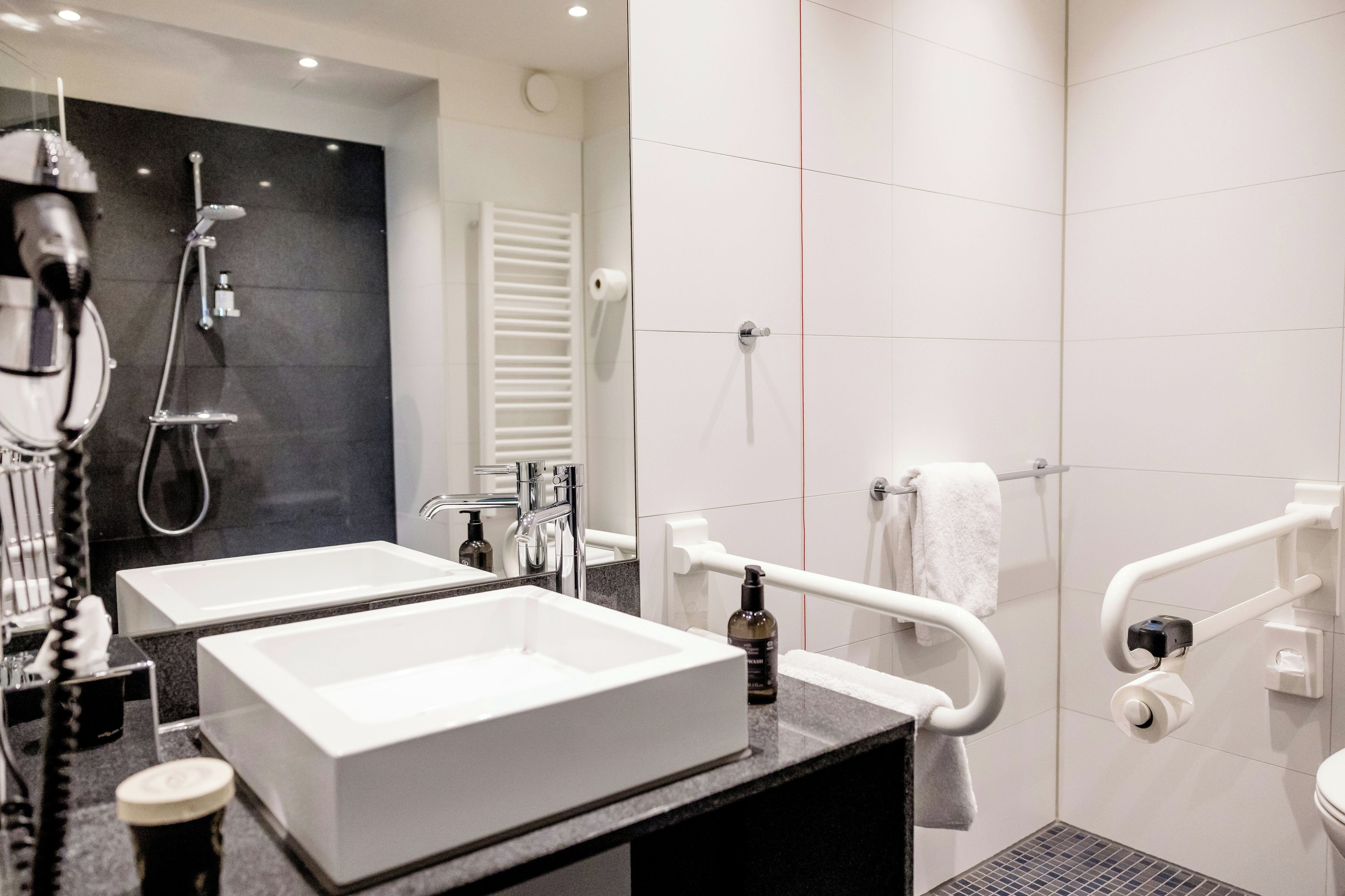 A modern bathroom with two sinks, a shower, and a toilet.