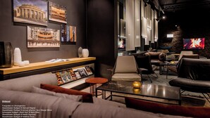 Een moderne zithoek met een bank, fauteuils, een salontafel en een tv-scherm waarop een haard wordt weergegeven.