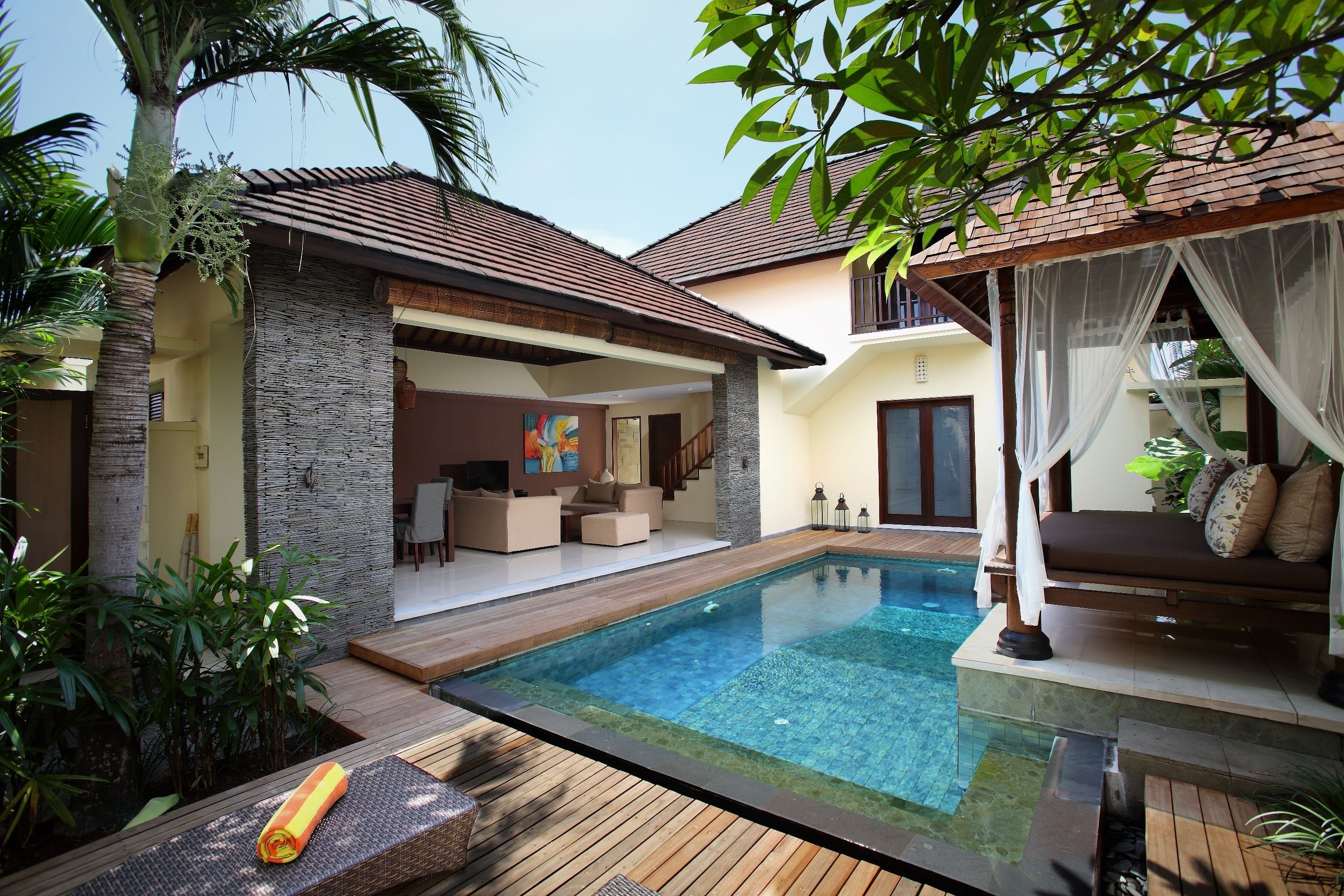 A modern house with a swimming pool, wooden deck, and a covered seating area.