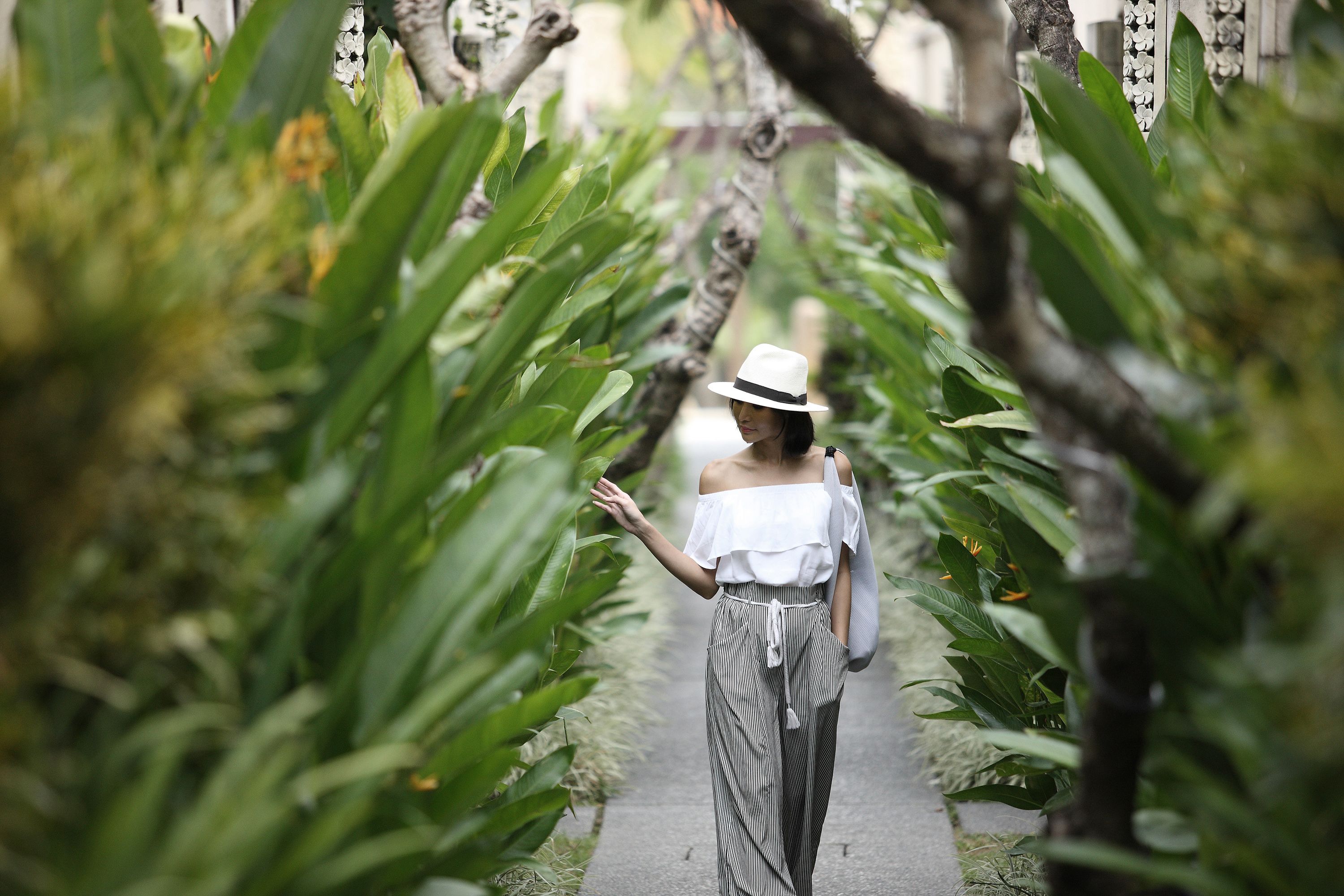 A person walking down a pathway surrounded by lush greenery.