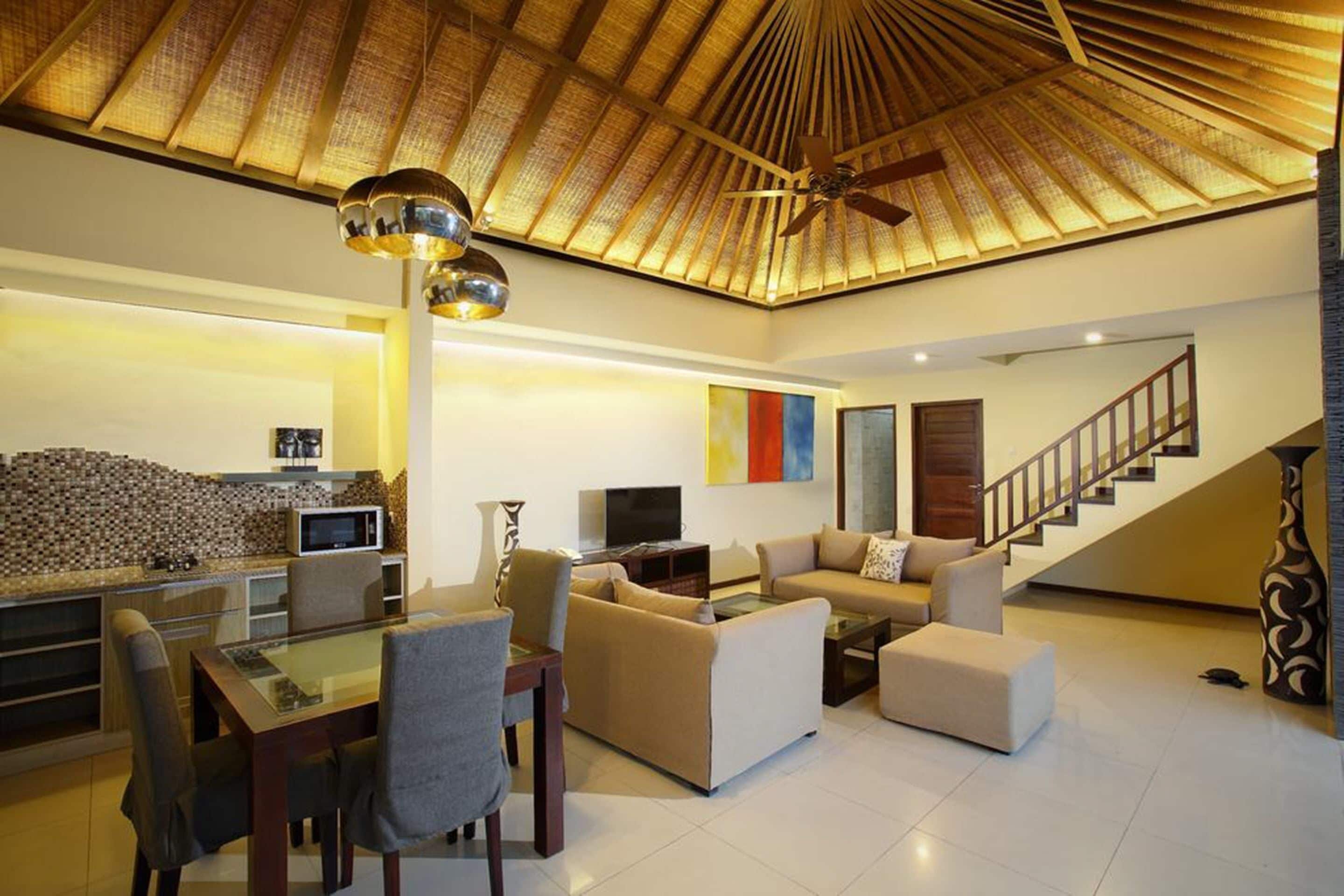A spacious living area with a high ceiling, a dining table, sofas, and a staircase.