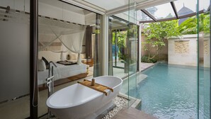 Un baño moderno con una bañera independiente, ducha con mampara de vidrio y vistas a una piscina.