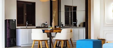 A modern kitchen with white cabinets, a dining table with four chairs, and a large mirror above the sink.