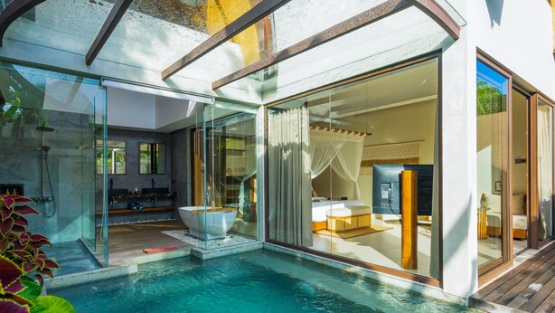Una villa moderna con piscina infinita cubierta con vidrio, un área de estar privada al aire libre y un salón espacioso con un gran ventanal.