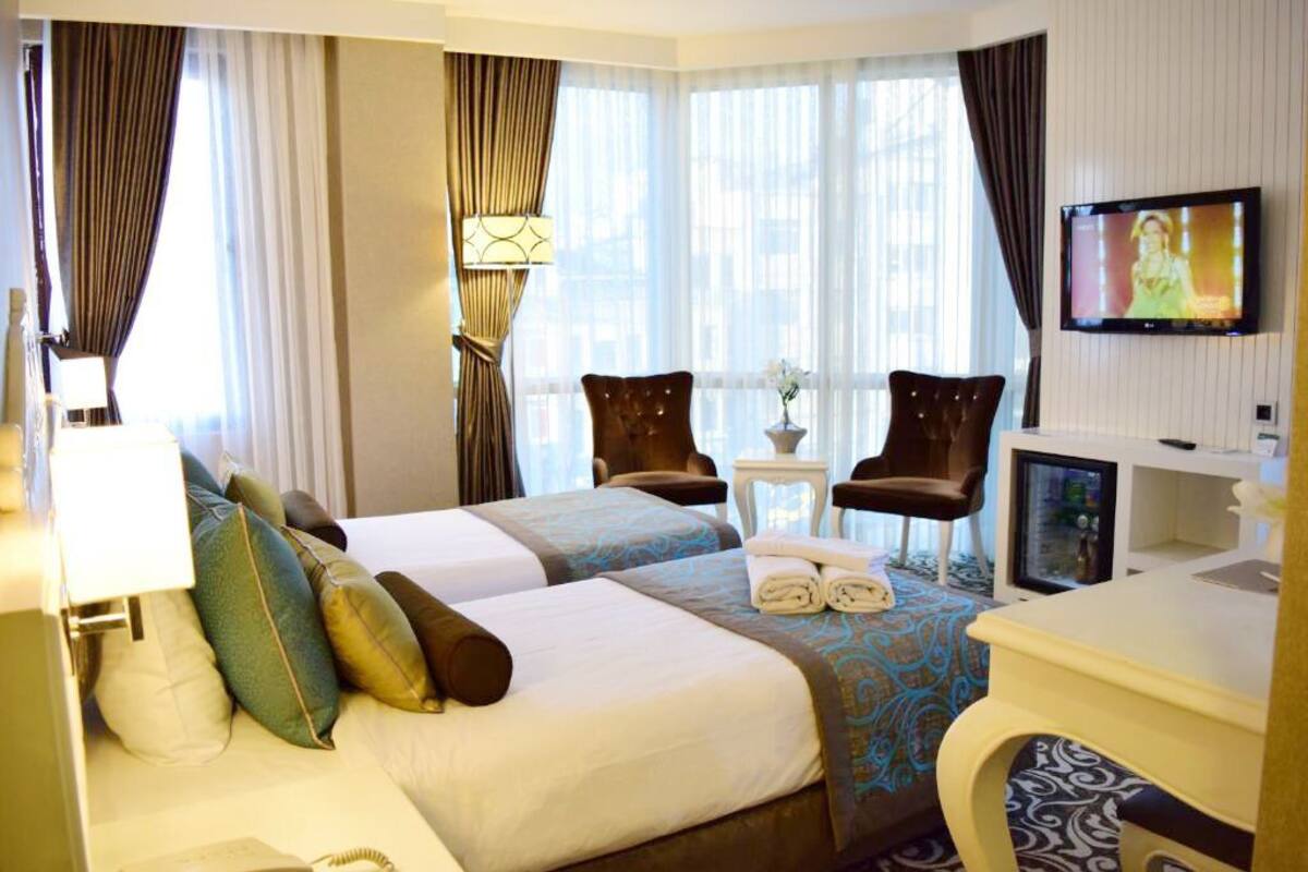 A hotel room with two beds, a TV, a desk, and a chair.