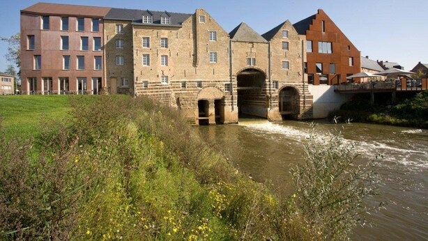 Un edificio histórico con varios arcos y un río frente a él.
