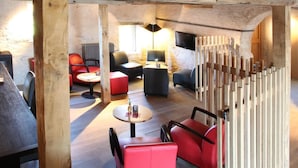 Un interior moderno con vigas de madera a la vista, asientos negros y rojos, y una mesa central.