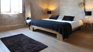Un dormitorio con una cama de madera, un tapete oscuro y un ventanal grande.