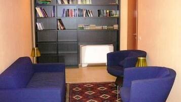 A room with a blue sofa set, a bookshelf, and a patterned rug.