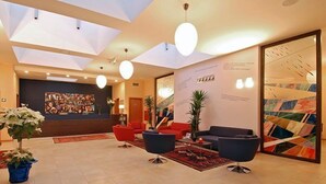 Een moderne lobby met een receptiebalie, een zithoek en kunstwerken aan de muren.