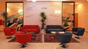 Een moderne lobby met rode en zwarte banken, een bijzettafeltje en een potplant.