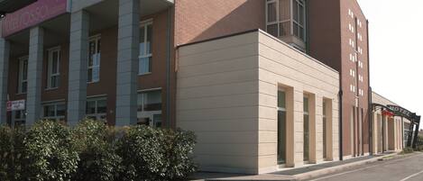 A hotel with a modern facade, featuring a mix of brick and beige panels, large windows, and a prominent entrance.