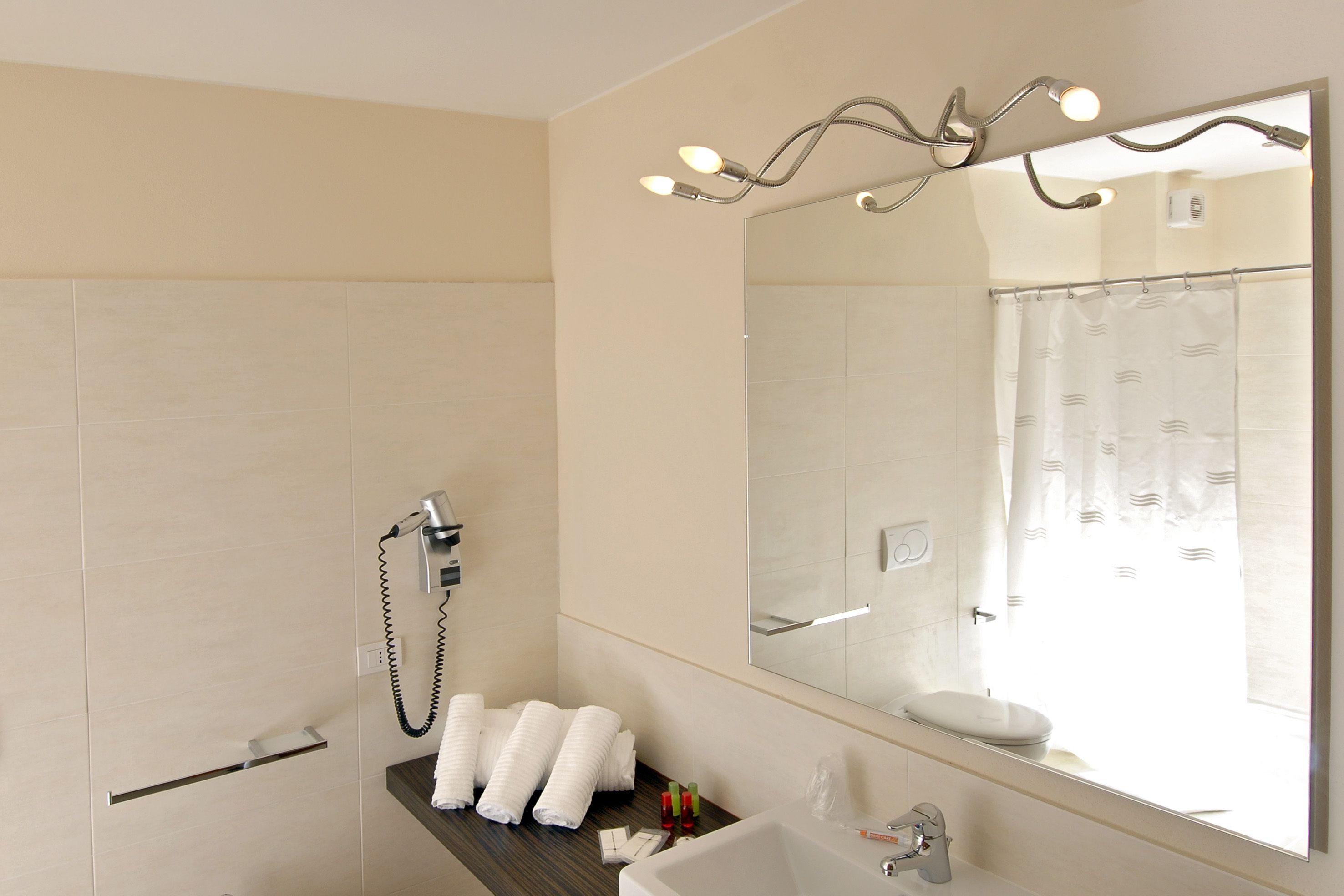 Une salle de bain moderne avec un grand miroir, une douche et un lavabo.