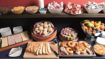Un bufé con una variedad de alimentos, incluyendo panes, pasteles y frutas.