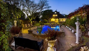 A pool area with a house in the background, surrounded by trees and outdoor furniture. - Forest Hall Guest House (Gqeberha (Port Elizabeth))