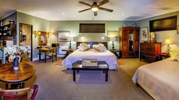 A hotel room with a bed, a desk, a chair, a table, and a ceiling fan.