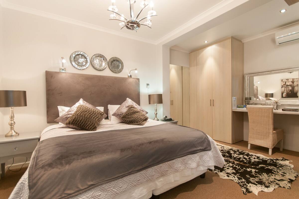Een moderne slaapkamer met een groot bed, een kledingkast, een bureau en een spiegel.