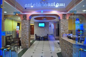 A lobby with a reception desk, seating area, and a TV screen. - Al Qidra Hotel Aqaba (Aqaba)