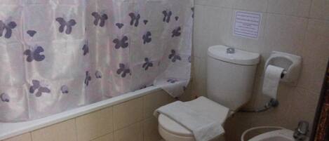 A bathroom with a toilet, bidet, and a shower curtain with a butterfly pattern.