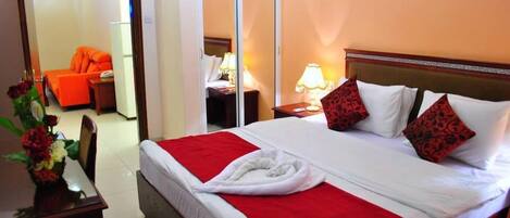 A hotel room with a bed, a wardrobe, a desk with a chair, and a mirror.