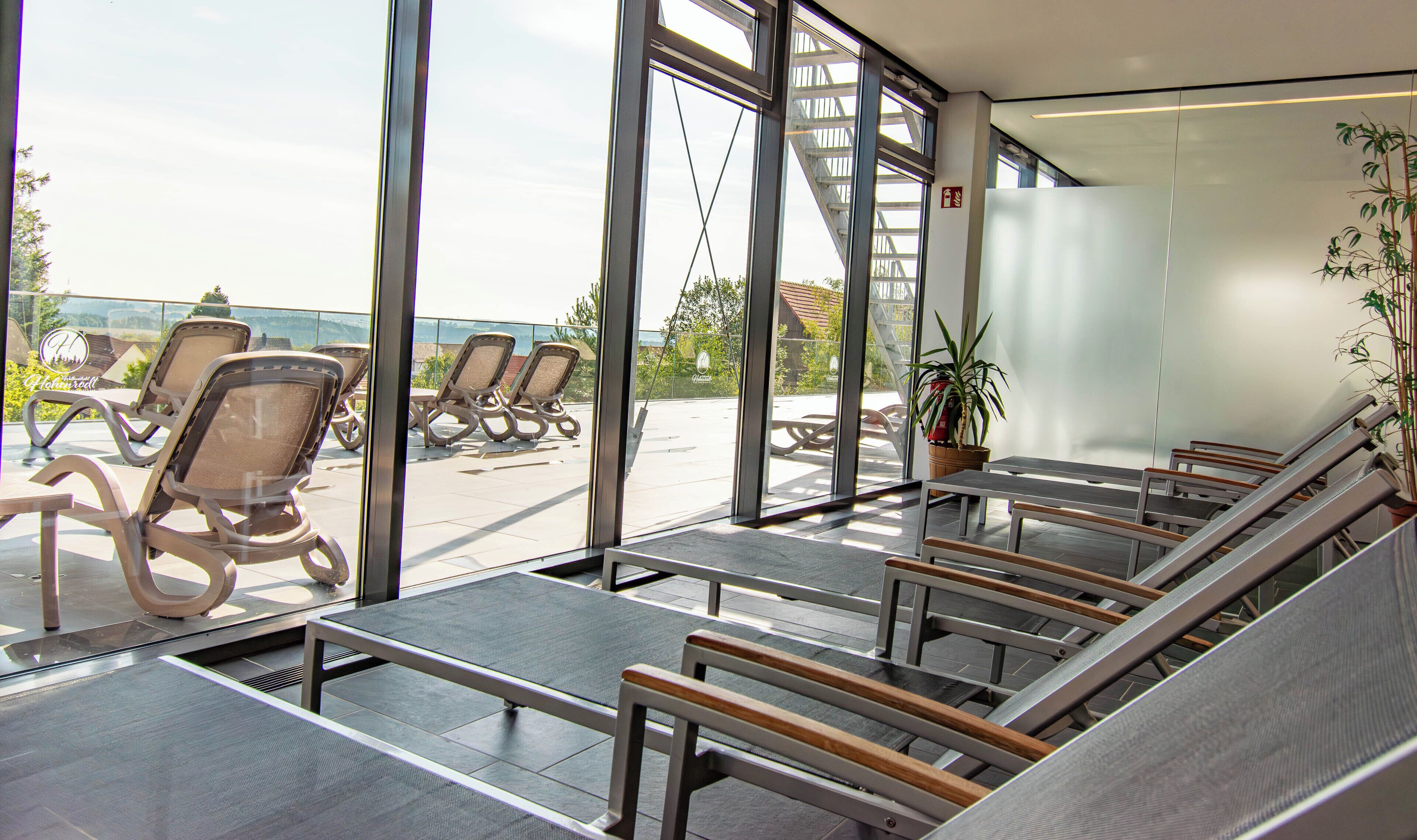 A modern hotel lobby with a seating area, large windows, and a view of the outdoors.