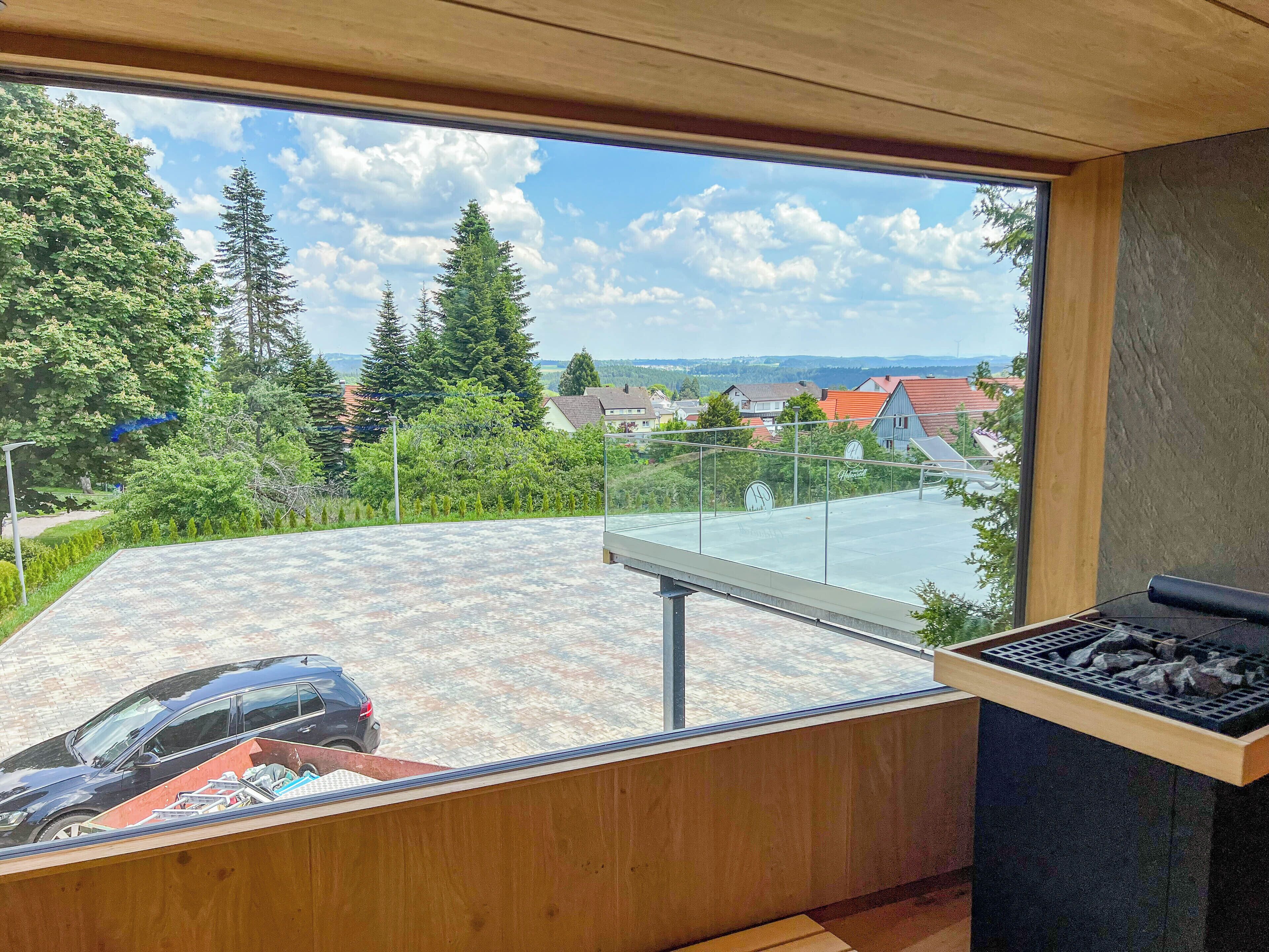 A balcony with a view of a car and a grill.