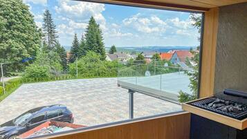A balcony with a view of a car and a grill.