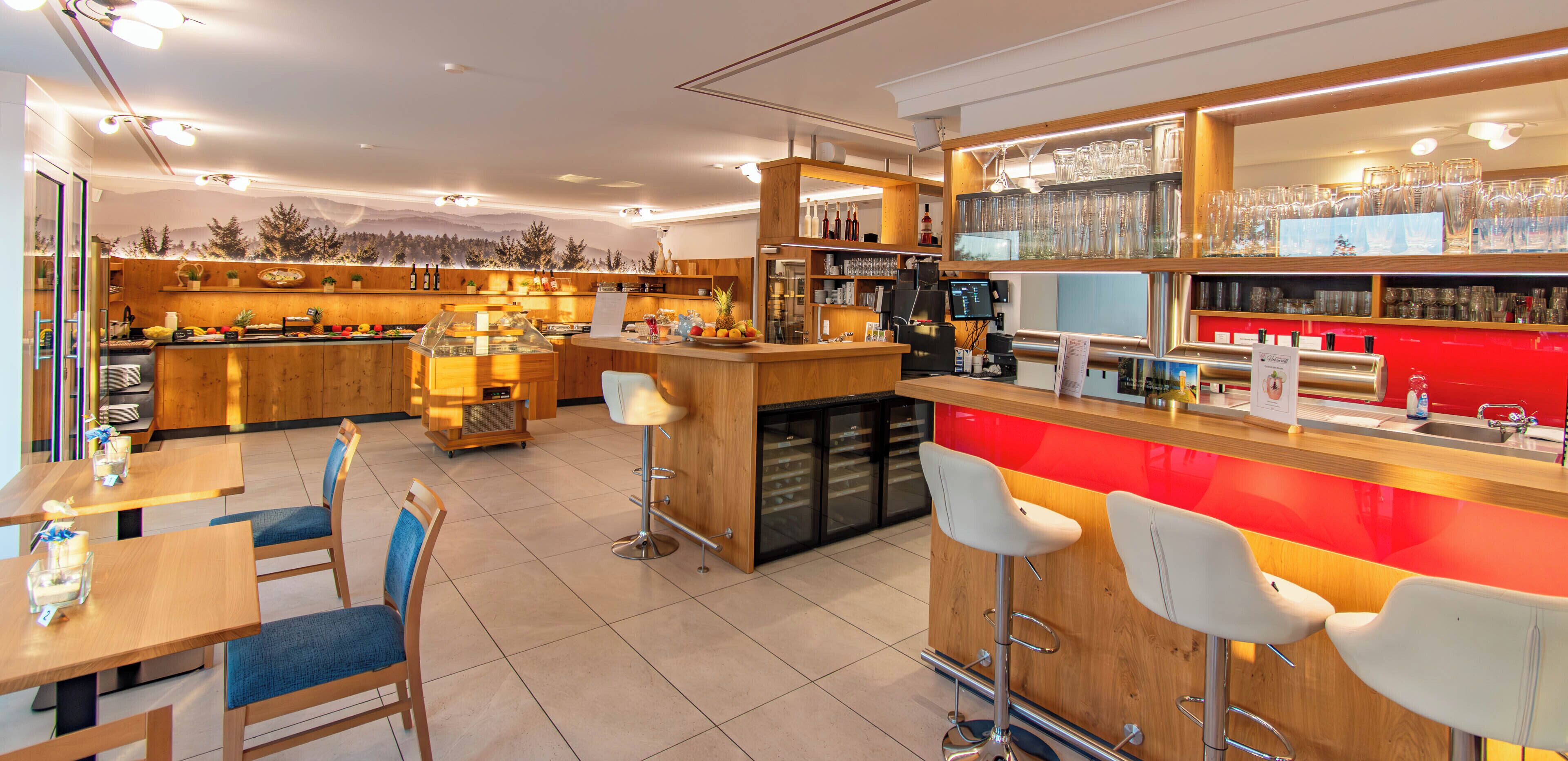 Zona de bar moderna con mobiliario de madera, una barra con caja registradora y estantes con cristalería.