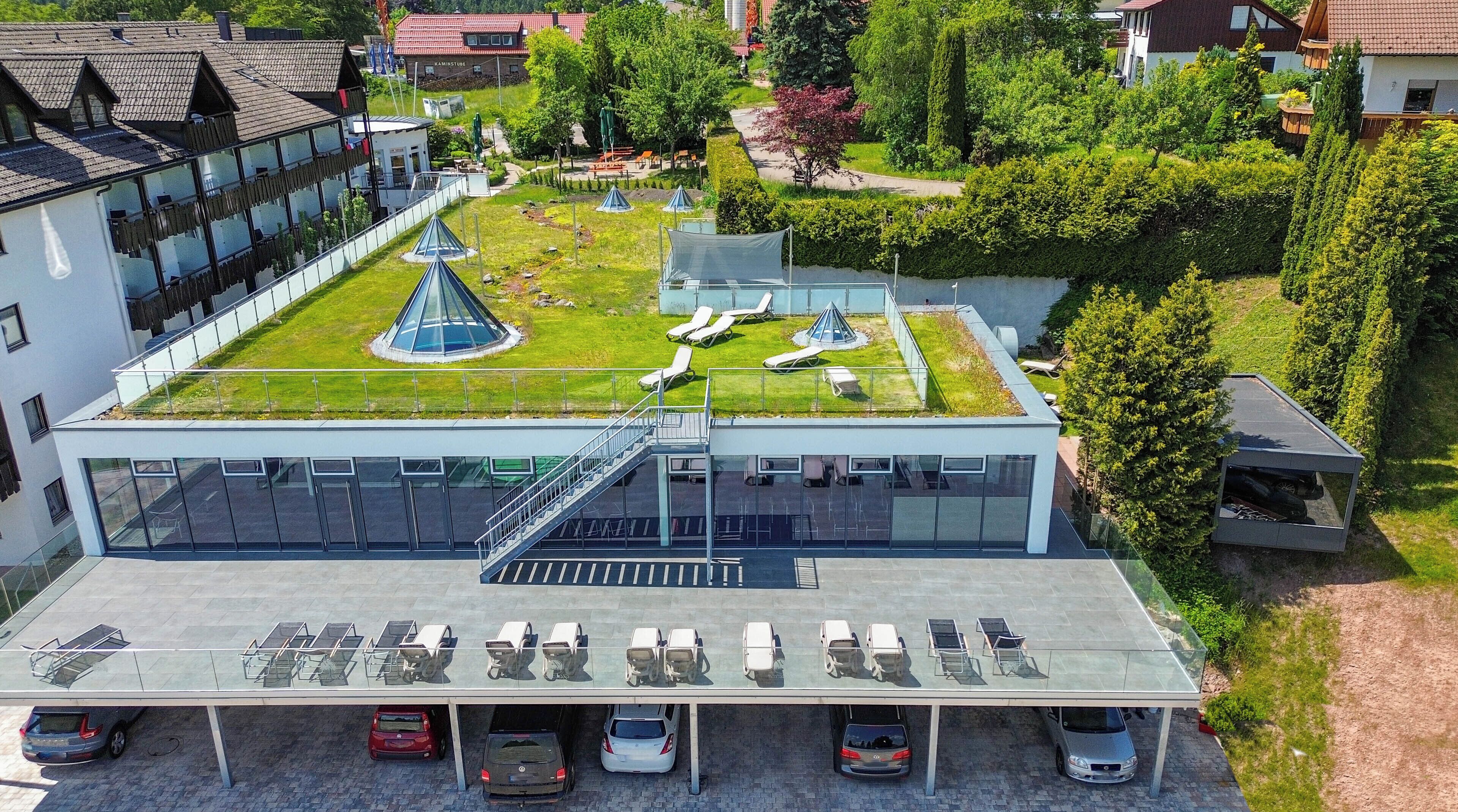 Un edificio moderno con jardín en la azotea, estacionamiento techado y piscina.