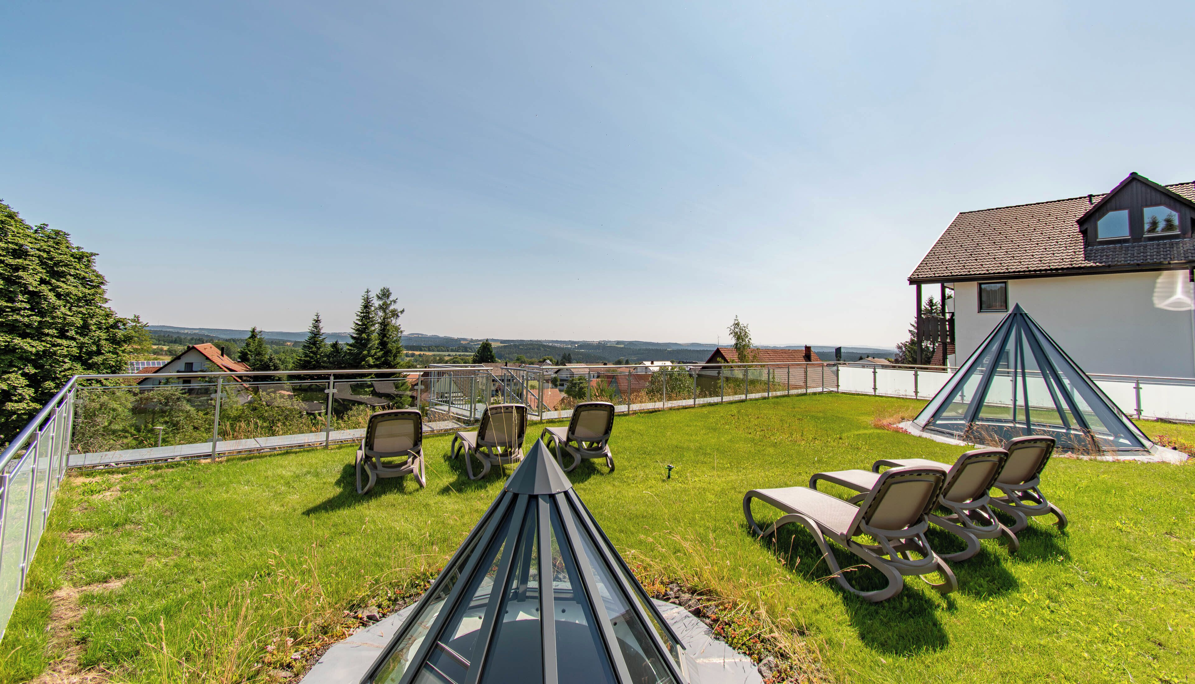 Eine Dachterrasse mit Außenmöbeln und Blick auf die umliegende Landschaft.