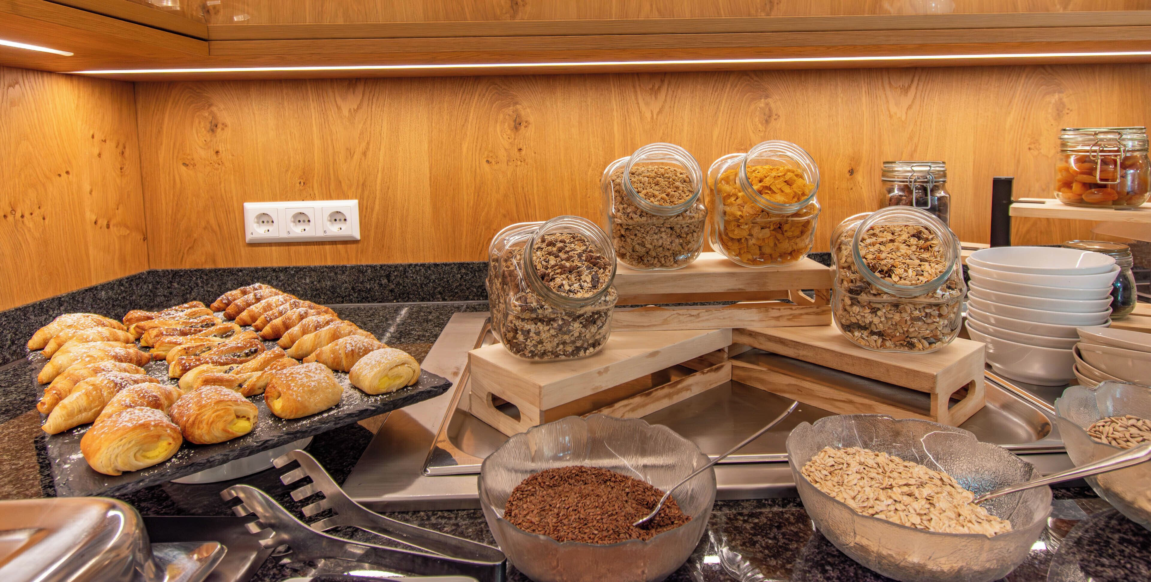 En buffet med kager, granola og skåle med cornflakes.