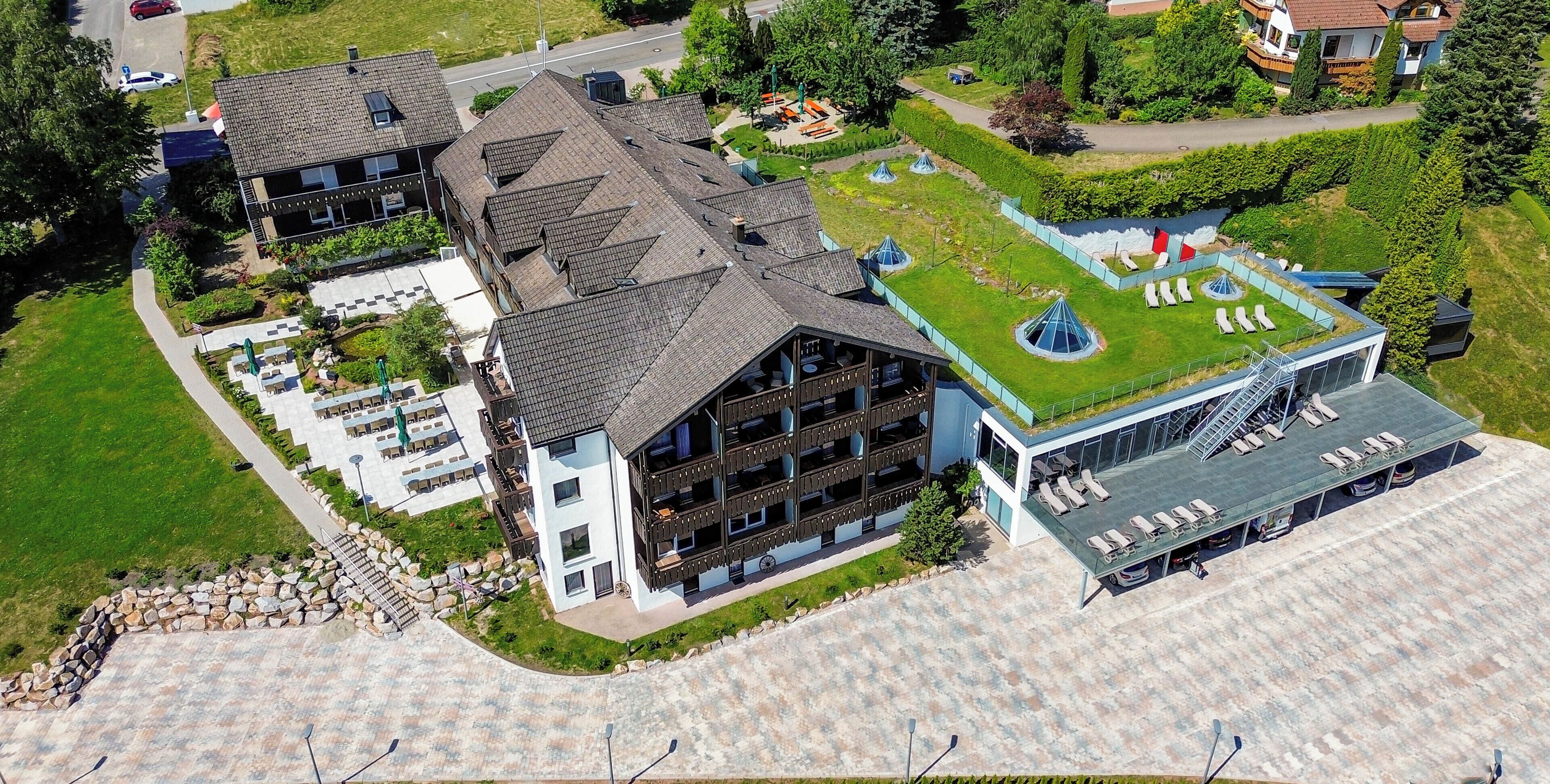 Un hotel moderno con diversi edifici, un giardino sul tetto e zone relax all'aperto.