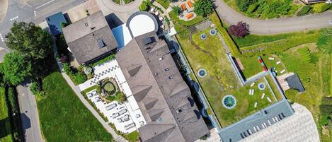 Vista aerea di un edificio con un ampio parcheggio, un giardino curato e una piscina.