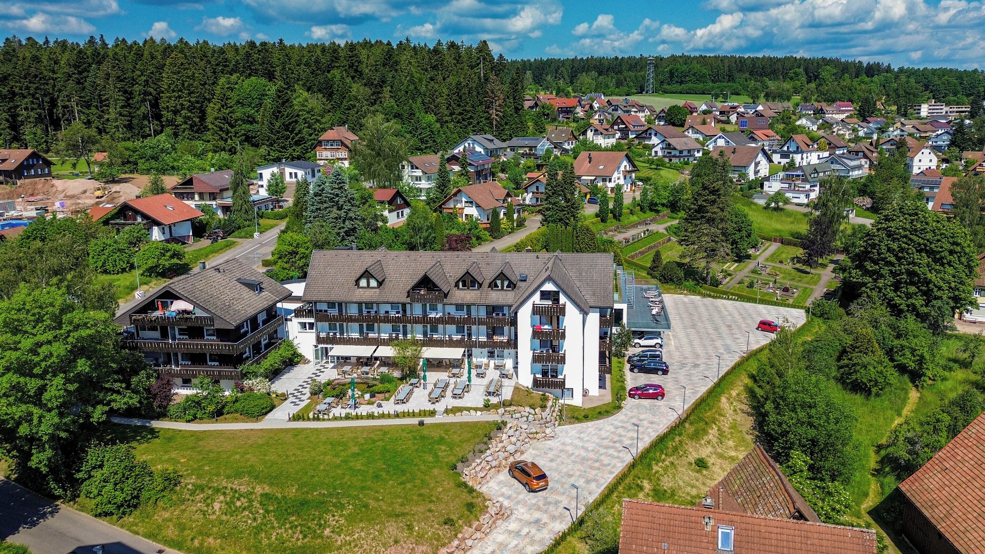 Luchtbeeld van een woongebied met een groot gebouw, meerdere balkons en een parkeerplaats.