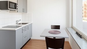 A modern kitchen with grey cabinets, a microwave, and a dining table with a chair. - Hotell Drott (Norrköping)