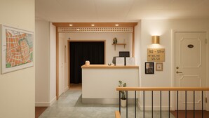 A reception area with a desk, a black curtain, a plant, and a door with room numbers. - Hotell Drott (Norrköping)