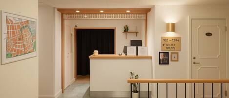 A reception desk with a sign indicating room numbers, a framed map on the wall, and a potted plant.
