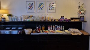 A breakfast bar with various food items, condiments, and a coffee machine. - Hotell Drott (Norrköping)