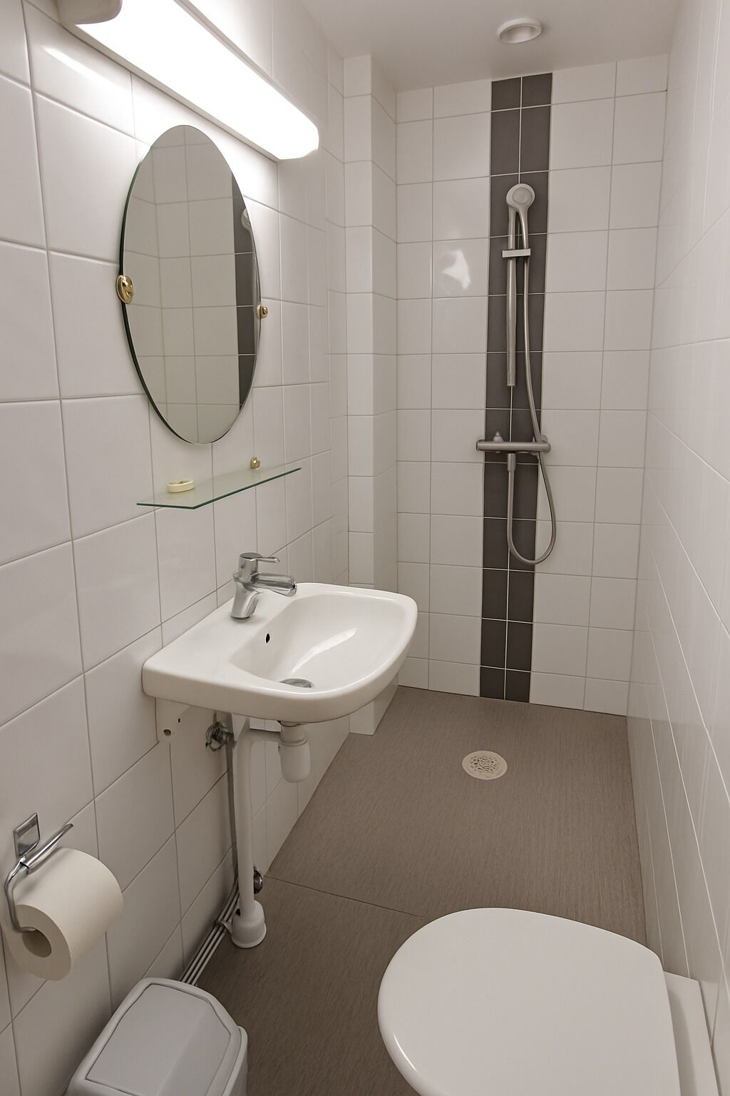 Un bany modern amb un lavabo blanc, un vàter i una dutxa.