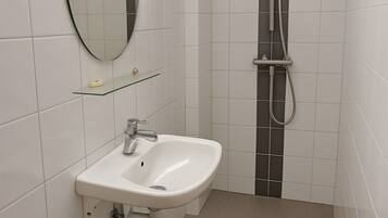Un bany modern amb un lavabo blanc, un vàter i una dutxa.