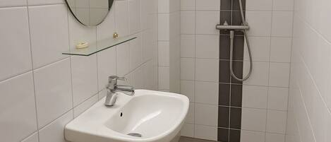 A modern bathroom with a white sink, a toilet, and a shower.