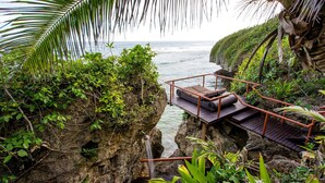 A wooden deck with a railing overlooking a rocky coastline and ocean.