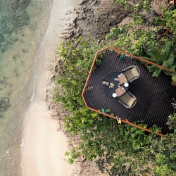 Relax on a deck surrounded by lush greenery and enjoy unobstructed views of the beach and clear waters.