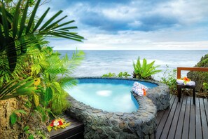 A stone pool with a wooden deck, surrounded by tropical plants, overlooking the ocean. - Namale Resort and Spa - Adults Only (Savusavu)
