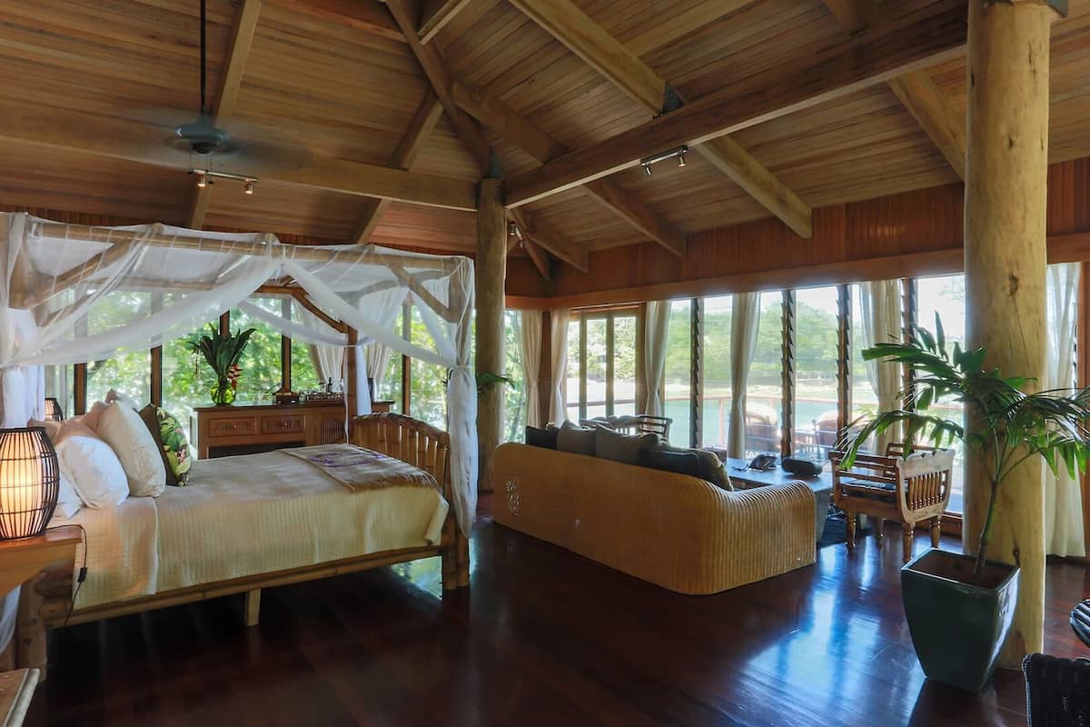 Una habitación amplia con una cama grande, un sofá y un comedor con vistas al exterior.