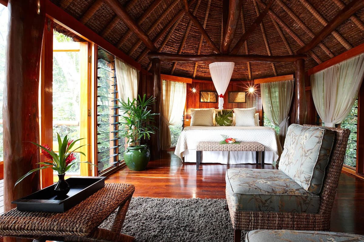 Una habitación con cama, sofá, mesa y una lámpara colgante.
