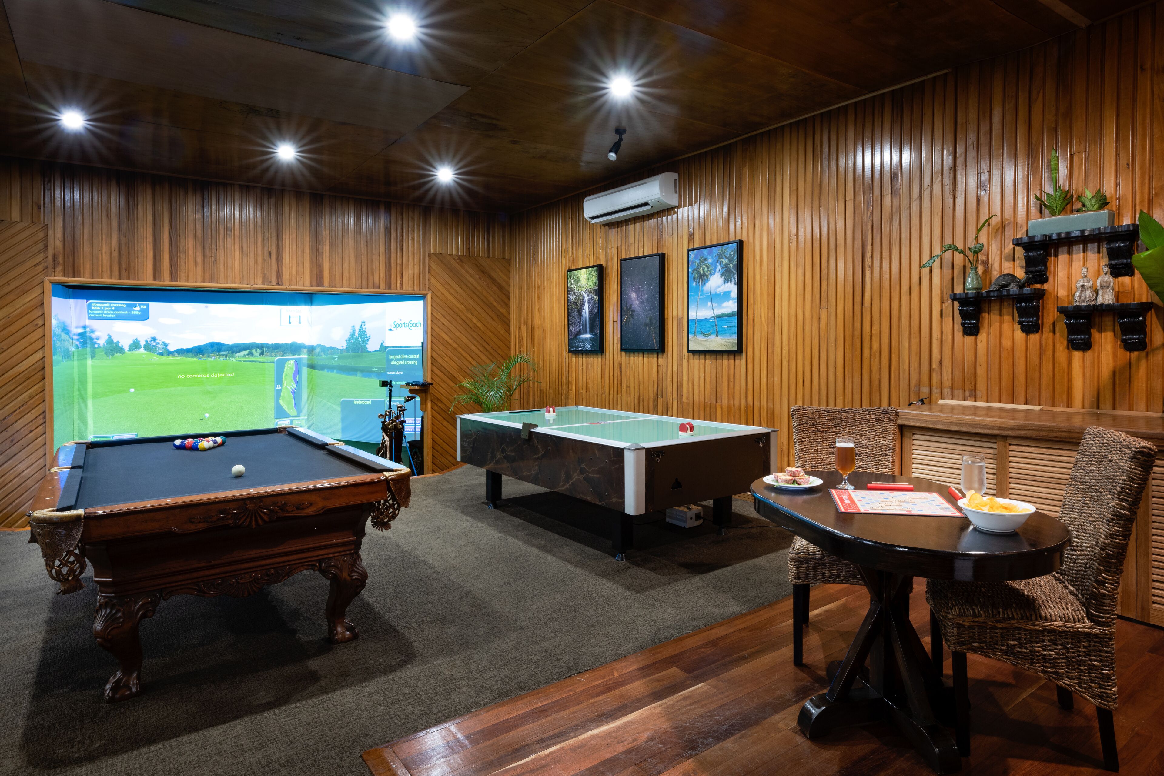 Una mesa de billar, una mesa de pool y una pantalla de televisión mostrando un campo de golf.