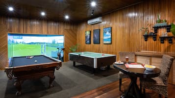 Una mesa de billar, una mesa de pool y una pantalla de televisión mostrando un campo de golf.